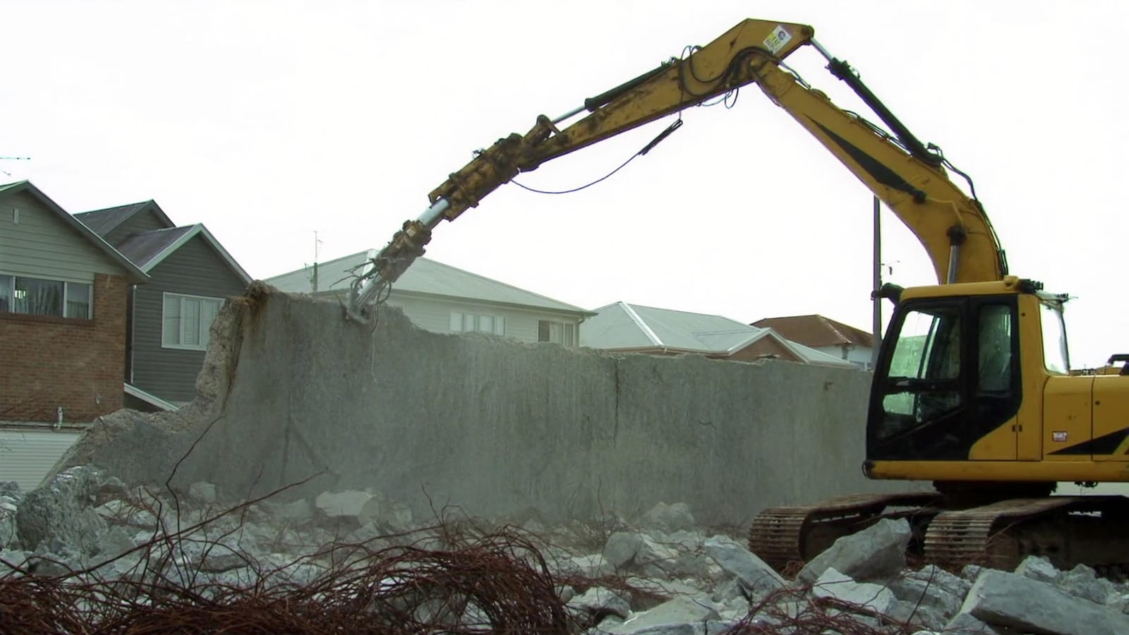 Excavator with a hydraulic breaker attachment demolishing a concrete wall